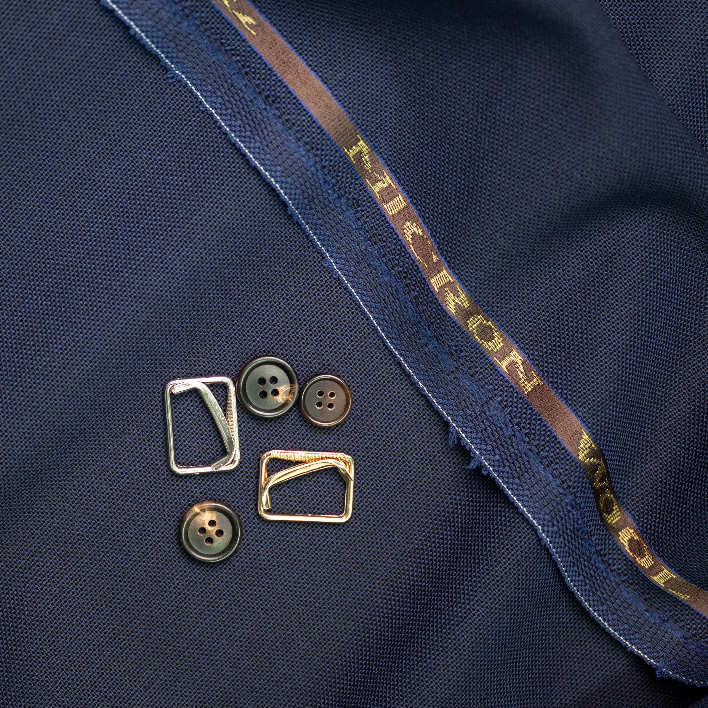 Close-up of buttons and a fabric edge with micron wool word on selvedge