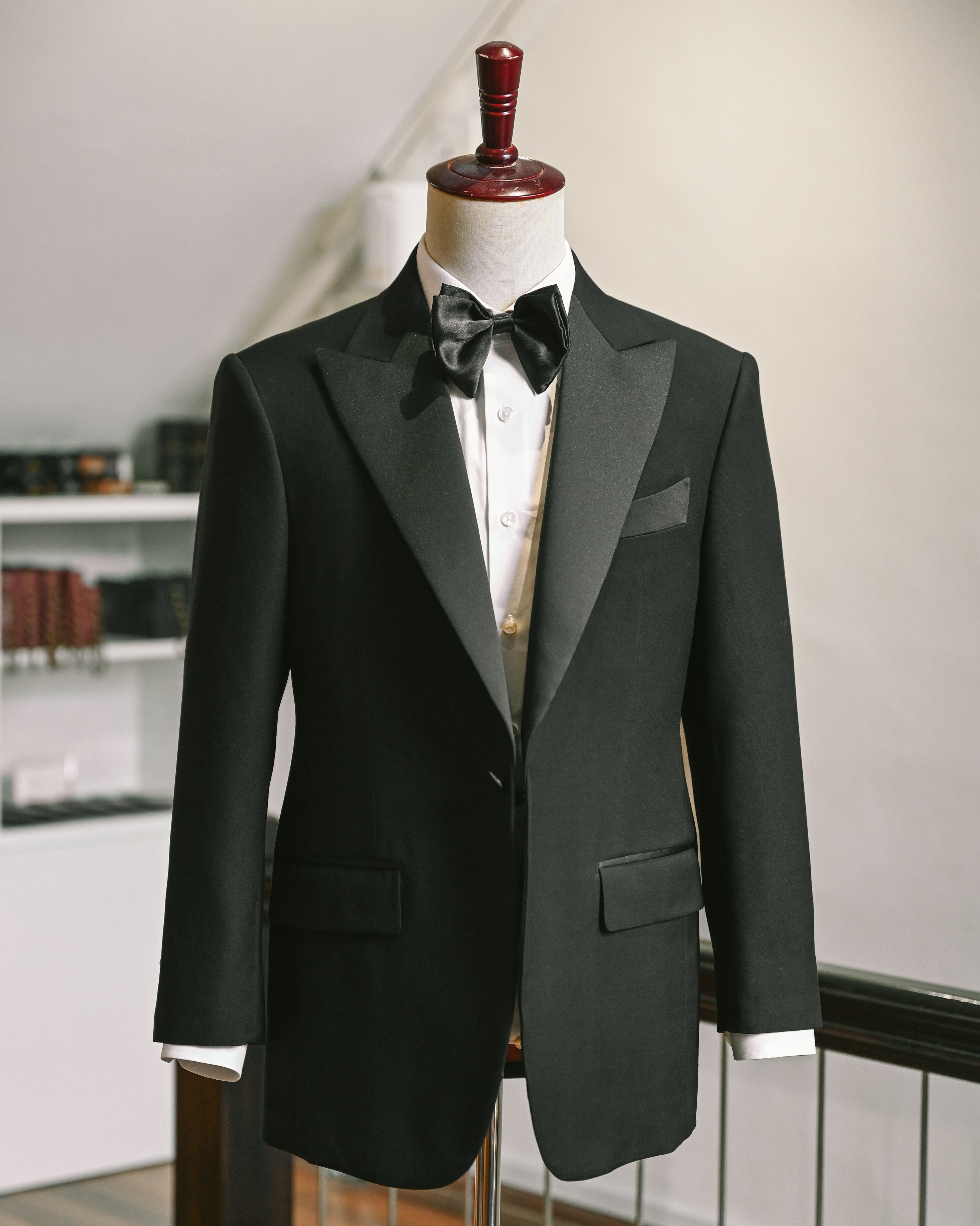 Black tuxedo jacket on a mannequin against a neutral background
