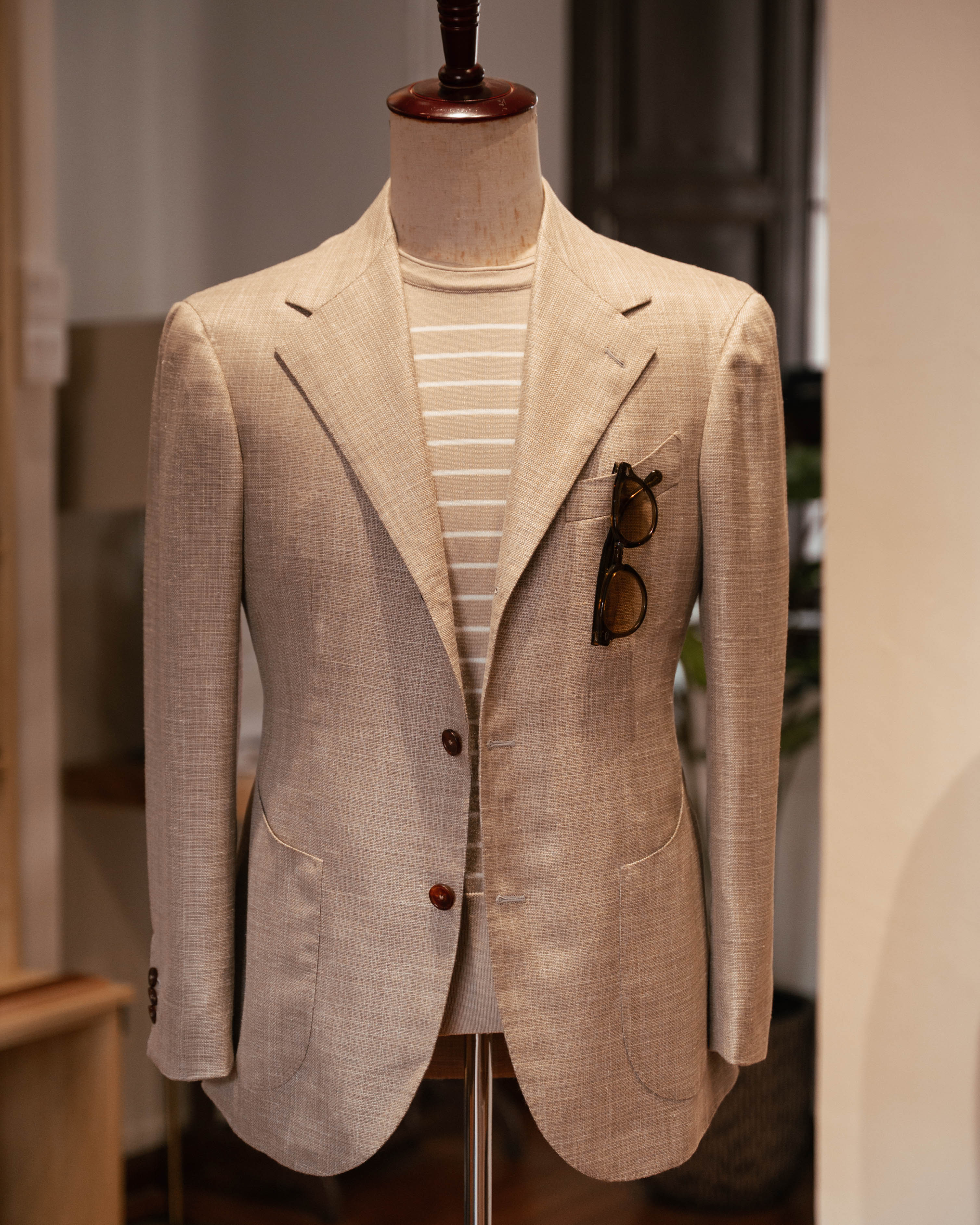 Beige blazer on a mannequin with sunglasses attached, blurred background